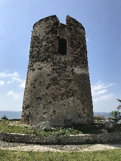 Torre redonda de piedra con una ventana en la parte superior, junto al mar.