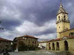 Square with church and buildings in Iurreta, Vizcaya, under cloudy sky.