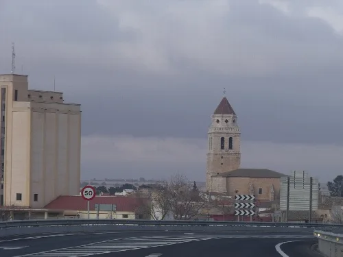 Vista de una torre y edificios en Mahora bajo un cielo nublado.