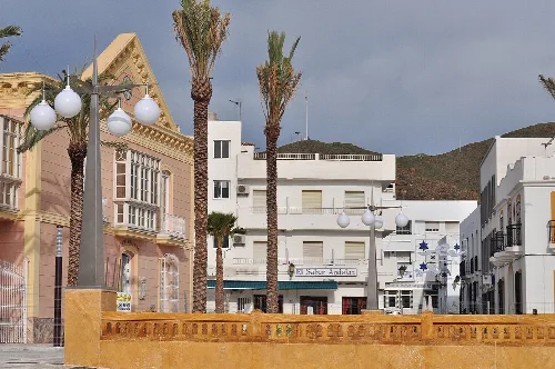 Plaza con palmeras, edificios blancos y farolas decorativas en Carboneras.