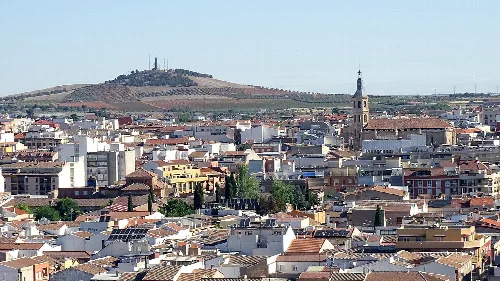 Vista de la ciudad de Valdepeñas con edificios y una colina en el fondo.