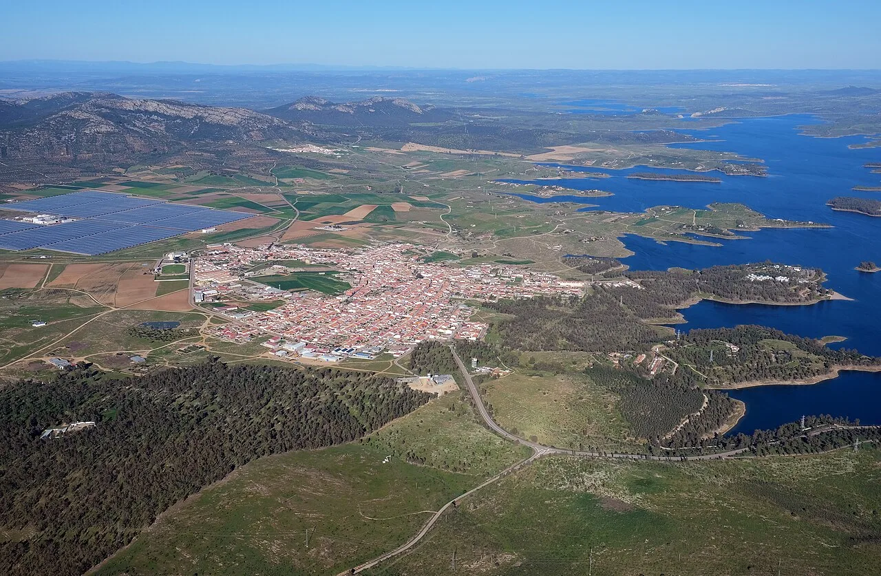 Vista aérea de un pueblo junto a un embalse y áreas rurales.