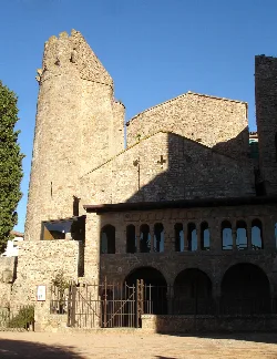 Steinturm und Mauern des Klosters Sant Feliu de Guíxols vor klarem Himmel.