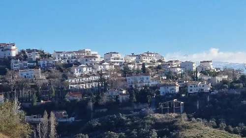 Weiße Häuser auf einem Hügel in Víznar, Granada, von der Straße aus gesehen.