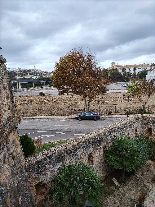 Bäume, ein Auto und alte Mauerruinen in Manilva.
