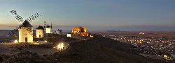 Windmills and a castle in Consuegra at sunset.