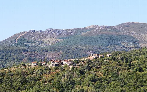 Vista de casas en un paisaje montañoso con vegetación.