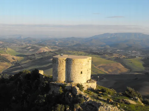 Stone tower in Montellano with mountainous landscape in the background.