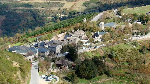Luftaufnahme von Piedrafita del Cebreiro mit Straßen und Gebäuden in einer grünen hügeligen Landschaft.