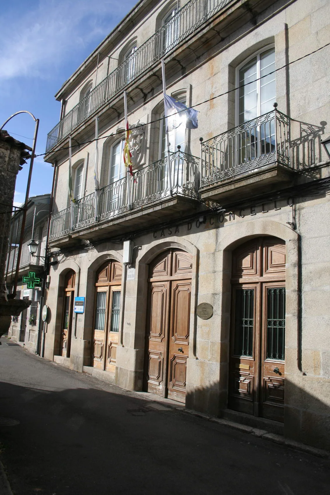 Edificio de varias plantas con puertas de madera y banderas en el balcón.