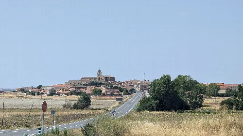 View of a town with a church on a hilltop and surrounding fields.