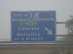 Cartel azul con flecha que indica dirección a Umbrete y Bollullos de la Mitación.