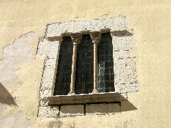 Gothic window with columns and stained glass on an old building facade.