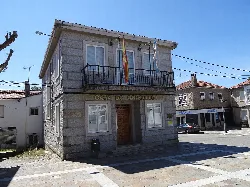 Edificio de la Casa do Concello de Riós con banderas en la fachada y calles alrededor.
