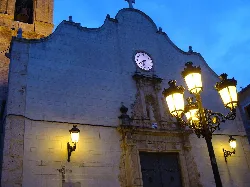 Fassade einer alten Kirche mit Uhr und Straßenlaternen.