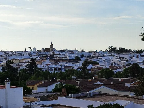 Vista de la ciudad con muchas casas blancas y una torre en el centro.