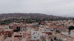 Vista de un pueblo con casas blancas y montañas en el fondo.