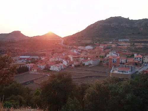 Vista panorámica de un pueblo con casas y montañas al atardecer.
