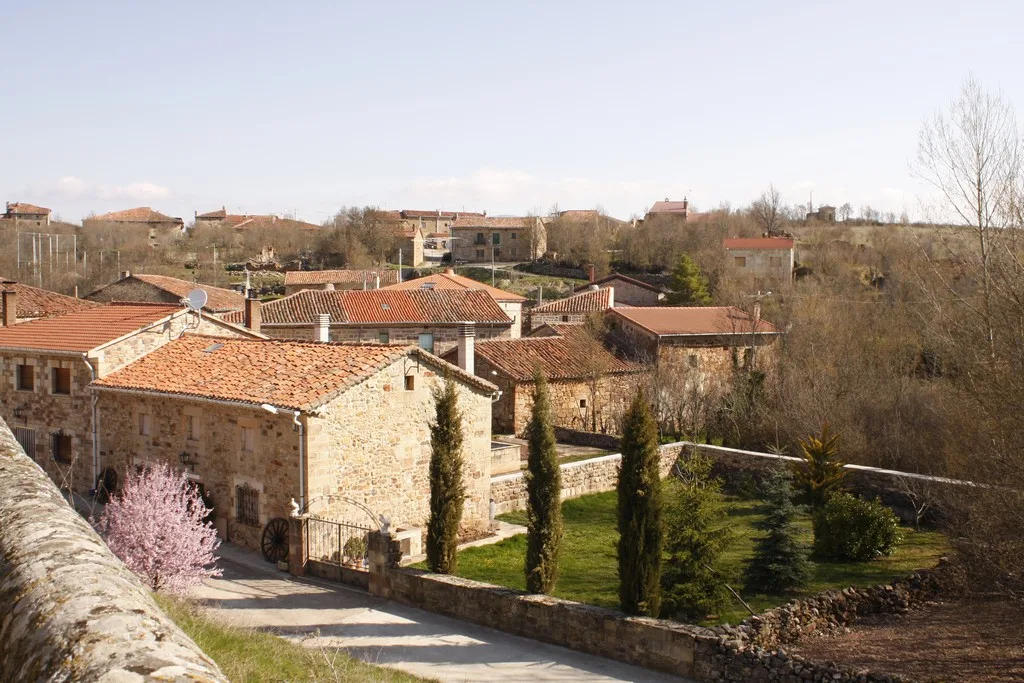 View of stone houses and a garden with trees in Jaramillo Quemado, Burgos.