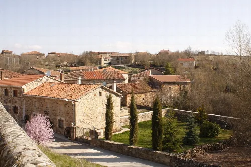 View of stone houses and a garden with trees in Jaramillo Quemado, Burgos.