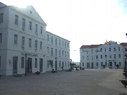 Large white building with multiple windows and a Town Hall in San Roque square.