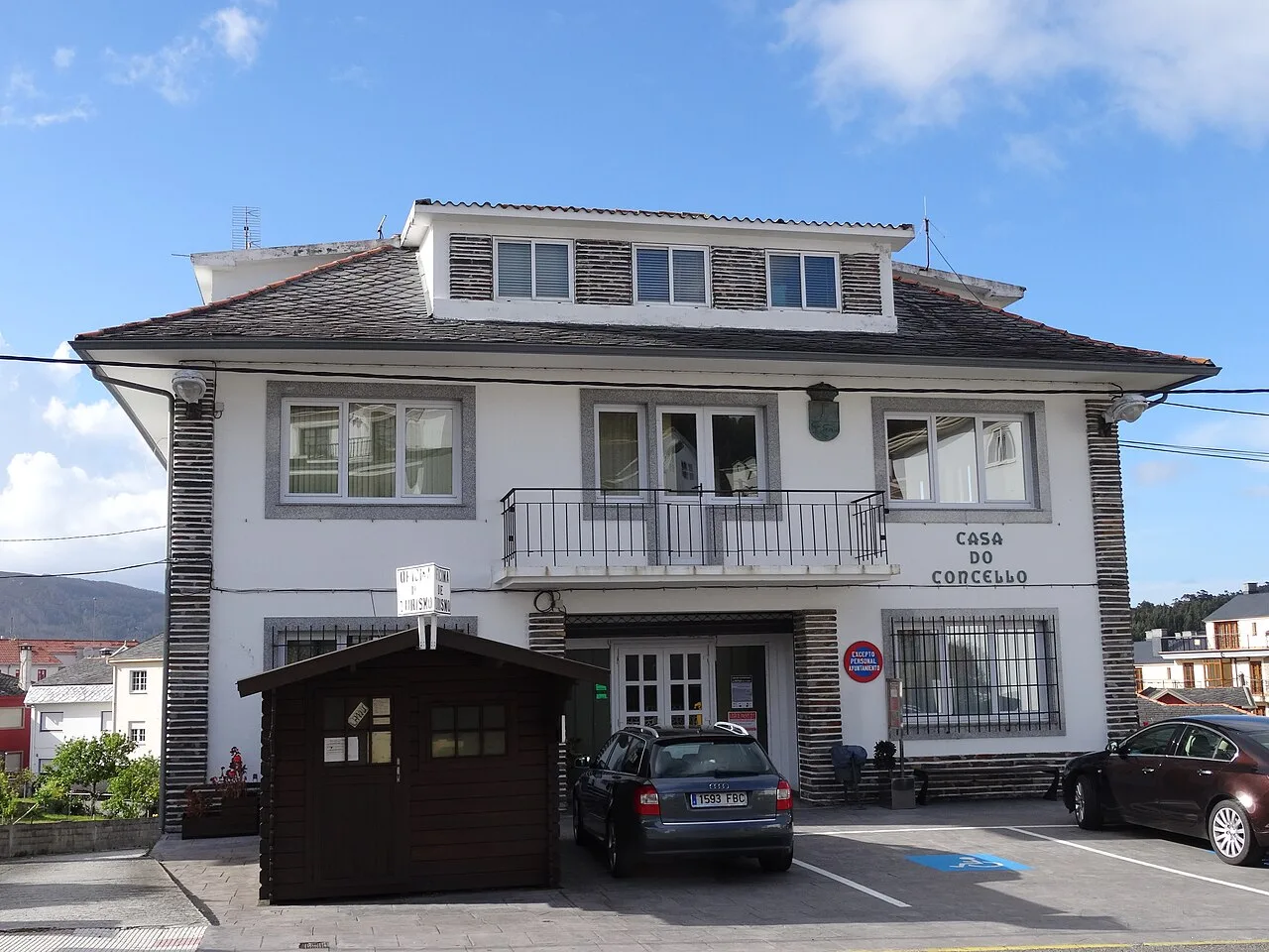 White building with a sign 'Casa do Concello' and cars in the street.