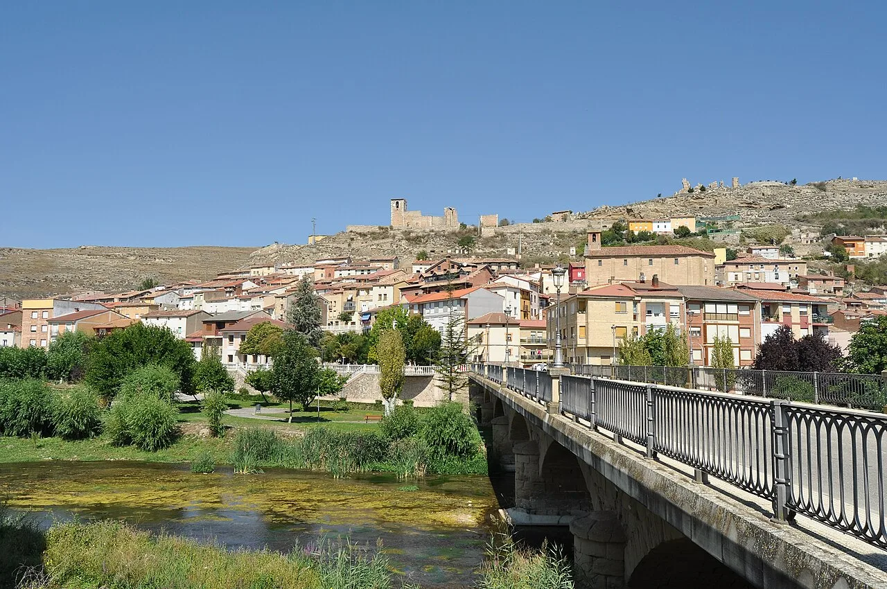 Brücke über den Fluss mit Häusern und einer Burg auf dem Hügel.