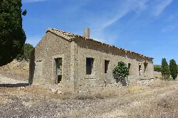 Edificio de la antigua estación de ferrocarril con paredes de piedra y ventanas sin cristales.