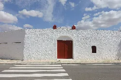 White facade with wooden door and arch at the bullring.