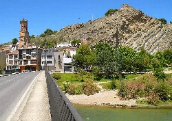 Bridge over the Arga River with buildings, church, and mountain in Peralta.