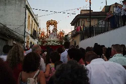 Procesión con una imagen religiosa decorada en una calle de Guadalcázar.