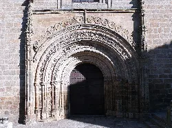 Arco de piedra con varias molduras y detalles decorativos en la entrada de una iglesia.