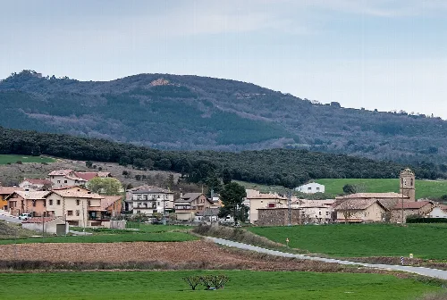 Landschaft von Abáigar mit Häusern, grünen Feldern und Bergen.