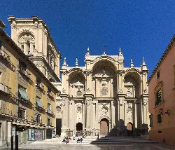 Vorderansicht der Kathedrale von Granada mit barocken Details und blauem Himmel.