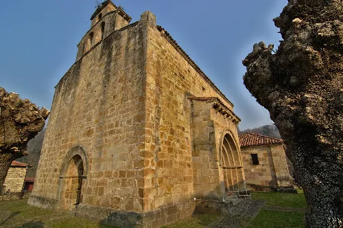 Iglesia parroquial de Silió vista desde el suroeste, con muros de piedra y arco en la entrada.