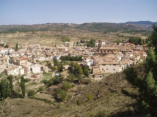 Blick auf eine Stadt in einer Hügellandschaft mit Häusern und Straßen.