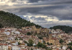 View of a hilltop town with white houses and an old church.