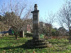 Steinmonument in einem Park mit kahlen Bäumen und blauem Himmel.