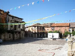Plaza con edificios antiguos y banderines de colores en Gumiel de Izán.