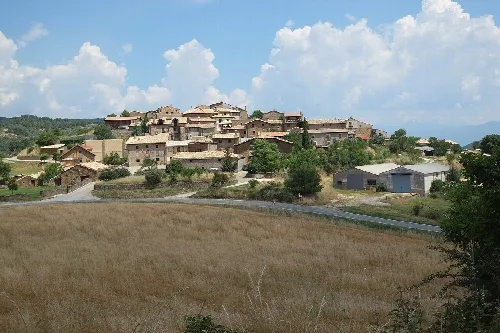 Pueblo en una colina con casas y campos abiertos en primer plano.