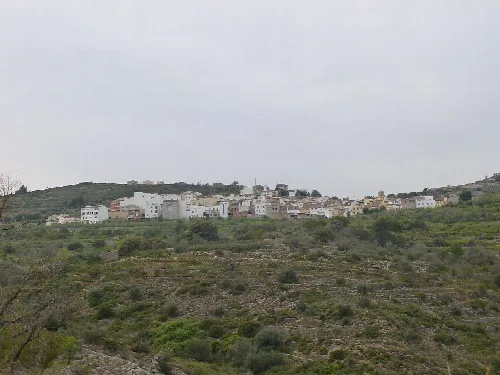 Vista panorámica de Costur con casas blancas en la colina.