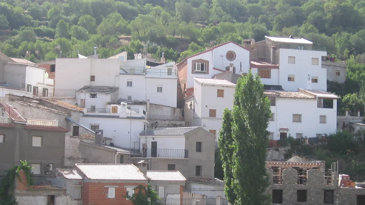 Panoramic view of white houses in Bacares with greenery and hills.