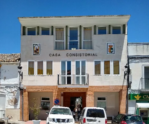 Building with coats of arms and parked cars on the street.