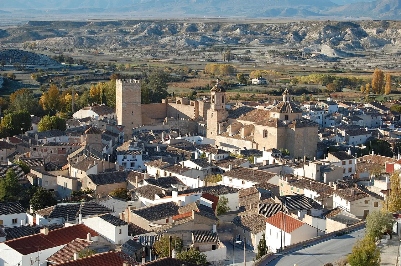 Vista de Orce con iglesia y casas en un paisaje montañoso.