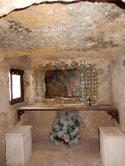 View of the interior of the hermitage with altar retablo and flowers.