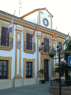 Town hall building with flags and a clock on the facade.
