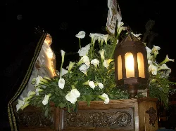 Flores blancas y una linterna en una carroza de madera en la Semana Santa de Sahagún.