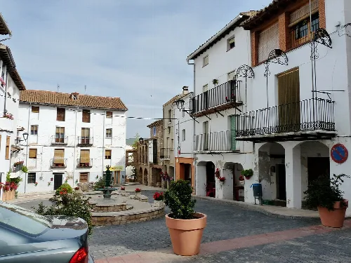 Square with porticoes, white houses, and fountain in Torrellas.