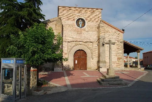 Steinernes Kirchendetail mit Rosettenfenster und Holztür in Flores de Ávila.