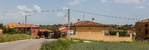 Traditionelle Häuser und Ortsschild in Rioseco de Soria.